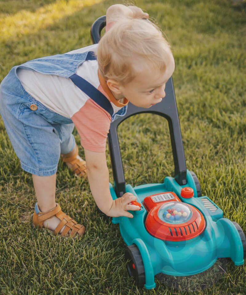Lapsed mängimas muruniidukiga aias