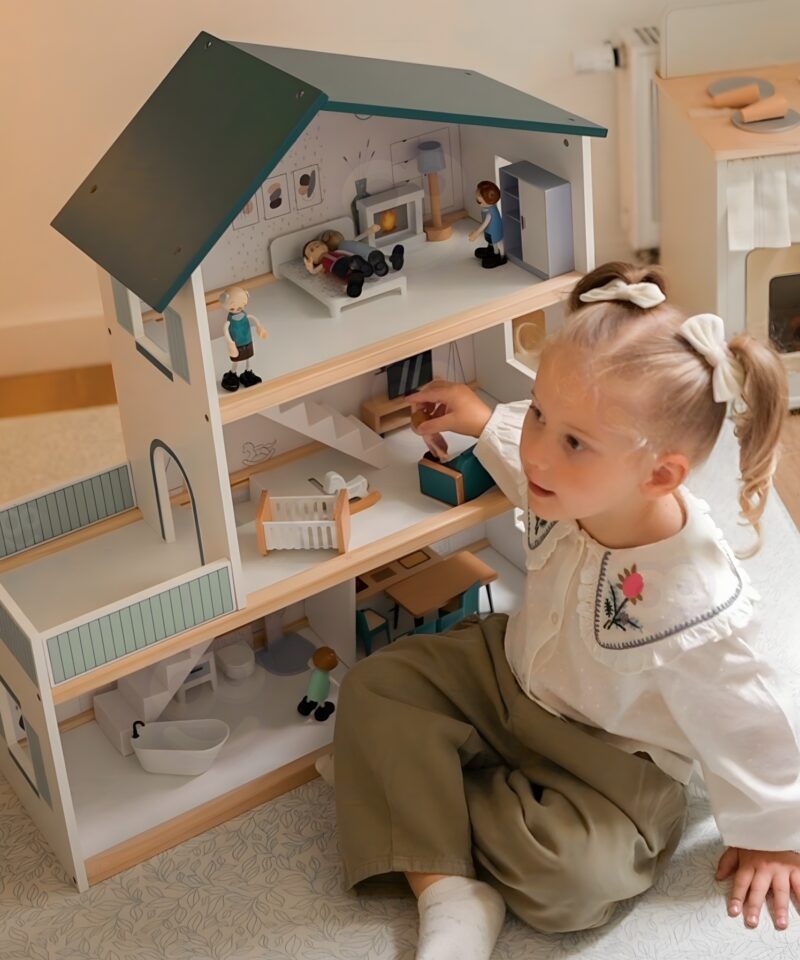 Nukud mängivad puidust nukumajas